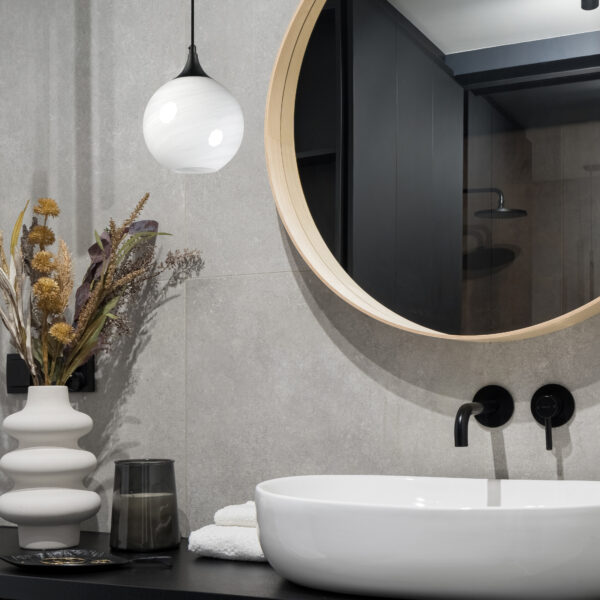 Close-up on elegant bathroom with big, round mirror over washbasin with black tap and stylish decorations; Shutterstock ID 2204320305; purchase_order: -; job: -; client: -; other: -
