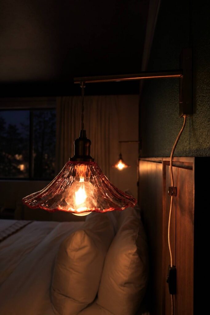 Sconce with brass arm and blush wavy glass sourced for The Buxton Hotel by The Light Center