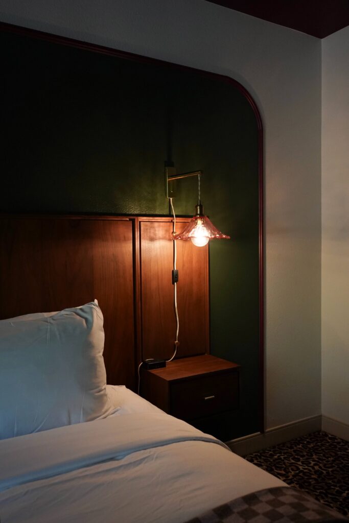 Guest room at The Buxton Hotel with a brass and blush wavy glass sconce sourced by The Light Center